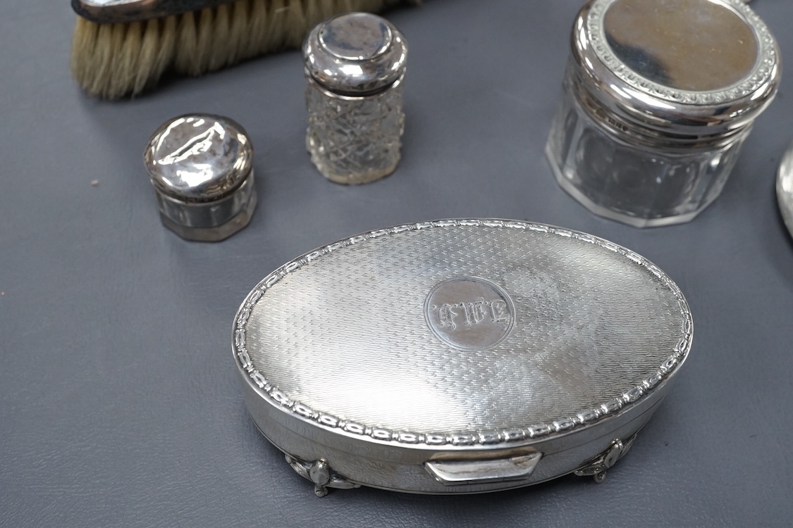A George V oval silver trinket box, Adie Bros. Birmingham, 1922, 10.8cm, together with a silver compact, four assorted silver mounted toilet jars and a silver mounted hair brush.